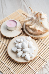 Background of seashell with white stones and candle on wooden mat. Travel summer holiday concept.