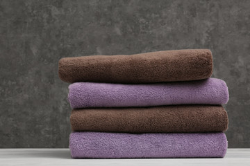 Stack of soft clean towels on table against color background