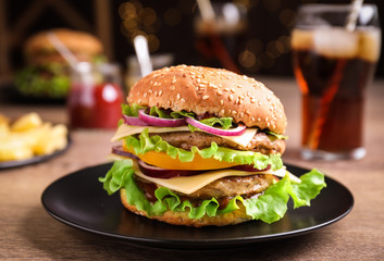Plate with delicious hamburger on wooden table