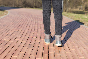 Legs of a girl in gray sneakers and black jeans are walking up the road, a symbol of the future,