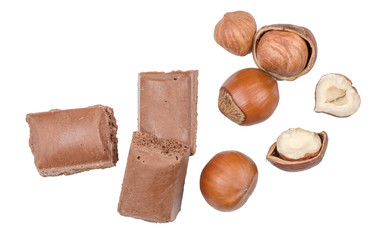 Chocolate pieces and hazelnut on white background, top view