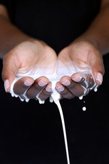 Black African hands cupped holding milk, pouring into hands for beauty industry