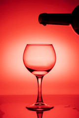 Wine glass with a bottle of wine on a red gradient background