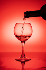 Wine glass with a bottle of wine on a red gradient background