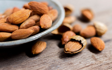 Roasted almonds, salt in dish of green on a wood table. Almonds are rich in nutrients, vitamins and minerals that are essential to the body.