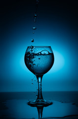 Wine glass with flowing white wine (water) on a blue gradient background