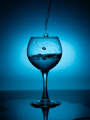 Wine glass with flowing white wine (water) on a blue gradient background