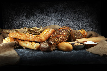 Assortment of baked bread and bread rolls on rustic grey bakery table background