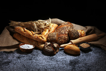 Assortment of baked bread and bread rolls on rustic grey bakery table background