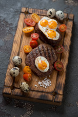 Rustic wooden serving tray with a pair of marbled beef steaks cooked in tuscan style, vertical shot