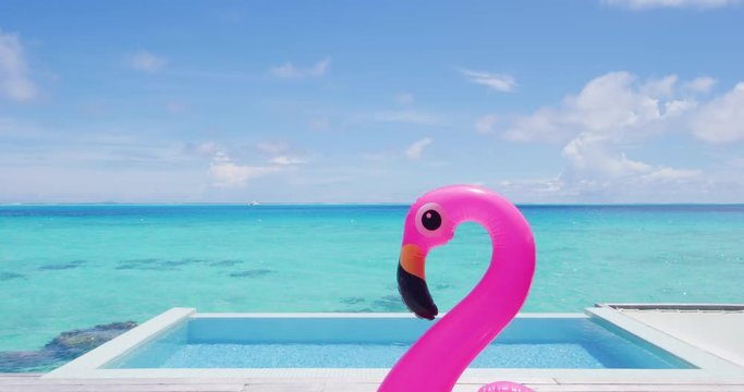 Funny vacation travel concept with inflatable pink flamingo float toy mattress in luxury swimming pool. Luxury lifestyle summer holidays travel background video.