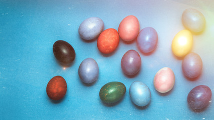 Colored Easter eggs lie in a row on a blue background, top view with copy-space