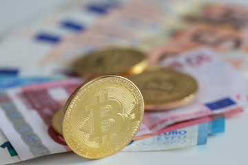 Bitcoins on first plan as virtual banknotes with real money on the desk