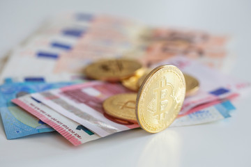 Bitcoins on first plan as virtual banknotes with real money on the desk