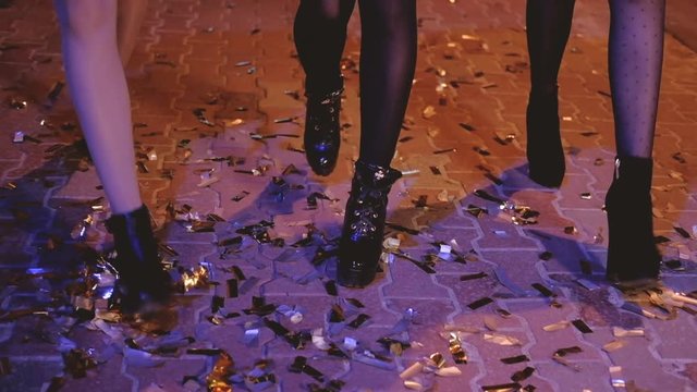 Girls night walk. City street covered with golden confetti left after open air party. Luxury celebration.
