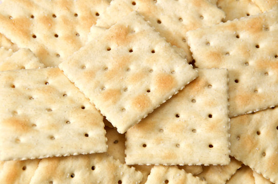 Close up of crackers filling entire image, known as saltines, soda and soup crackers.
