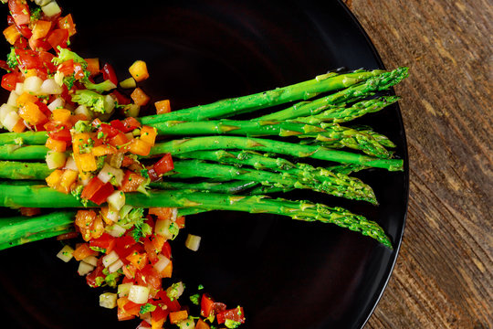 A traditional vegetarian salad from white asparagus, cocktail tomatoes and rugula with green on a rustic wooden table