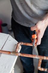 Fototapeta Closeup professional master plumber hands soldering copper pipes gas burner. Concept installation, plumbing replacement, solder flux paste, pipeline repair, professional master, pipe leakage obraz