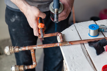 Closeup professional master plumber hands soldering copper pipes gas burner. Concept installation, plumbing replacement, solder flux paste, pipeline repair, professional master, pipe leakage - obrazy, fototapety, plakaty