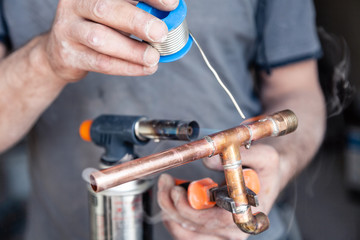 Closeup professional master plumber holding flux paste for soldering and brazing seams of copper...