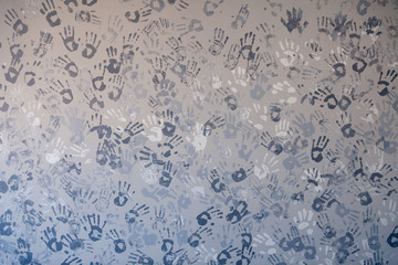 Close-up picture of a plurality of children's handprints painted on a gray wall. Textural background. Concept wall of memory in kindergarten, school