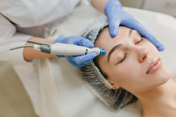 Naklejka premium Closeup portrait of beautiful woman during cosmetology therapy in beauty salon. Professional dermatology procedures, lifting, rejuvenation, modern devices, healthcare