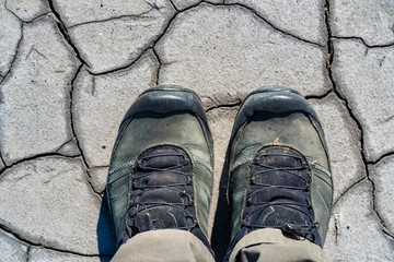 Top view hiking boots on dry muddy soil surface for background texture