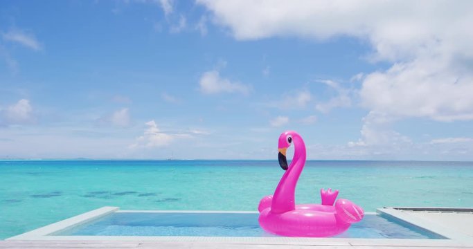 Vacation travel concept with inflatable pink flamingo float toy mattress in luxury swimming pool. Luxury lifestyle summer holidays travel background video.