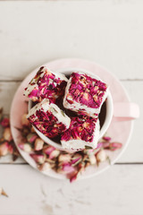 Turkish delight with rose petals. Nougat with edible flowers in a pink coffee cup. Lebanese sweets