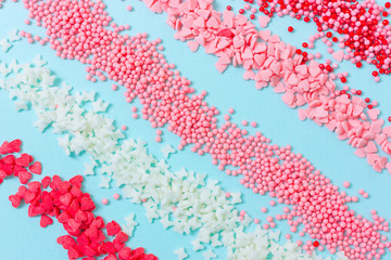 Colorful sugar sprinkles on blue background. Top view of confectionery toppings