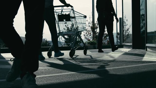 People buying from supermarket with carts, entering shop