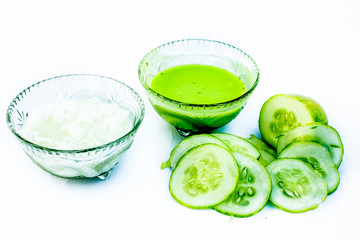 Naklejka na ściany i meble Cucumber face pack isolated on white i.e. Cucumber pulp well mixed with dahi or yogurt in a glass bowl and entire raw ingredients present on the surface.Used to cure acne prone skin.