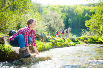happy young woman smiling and touching water in rapid river 