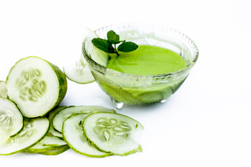 Cucumber face pack isolated on white i.e. Cucumber juice well mixed with gram flour in a glass bowl and all the raw ingredients present on the surface.Used for instant glow.