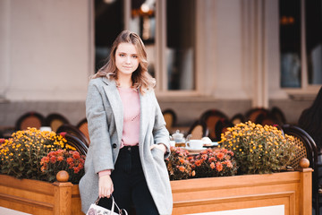 Beautiful blonde girl 16-17 year old wearing stylish jacket posing at city background. Looking at camera. Spring season.
