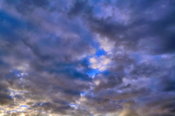 Obraz premium Blue sky with gold clouds - dramatic sunset, beautiful natural background. Setting sun illuminates the clouds.