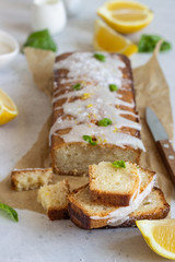 Homemade glazed lemon loaf cake decorated with lemon zest, basil and coconut chips.