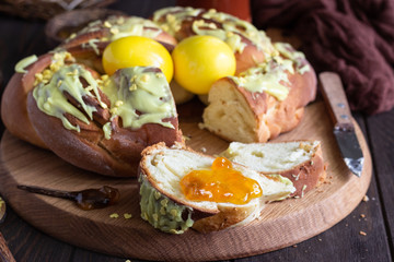 Swirl brioche with citrus glaze decorated with painted yellow eggs. Braided or roll bread, Babka. 