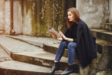 Beautiful girl sitting.The woman is sitting on the stairs. Lady with a tablet