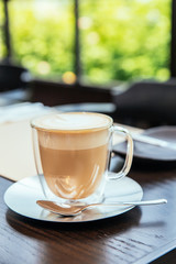 Front view of Hot Cappucino with blur green background. White froth on coffee and milk with copy space.