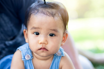 Close up portrait of little Asian baby girl sitting in the park