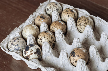 Motley quail eggs in a paper substrate on a wooden vintage table. Soft focus. Macro.