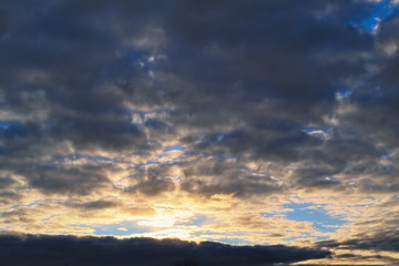 Naklejka na ściany i meble Blue sky with gold clouds - dramatic sunset, beautiful natural background. Setting sun illuminates the clouds.