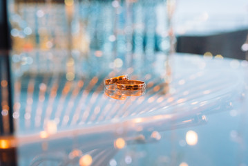 Gold wedding rings lie on a glass table close-up