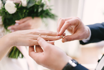 The bridegroom puts the wedding ring on the bride close up. The bride puts the bridegroom on the...