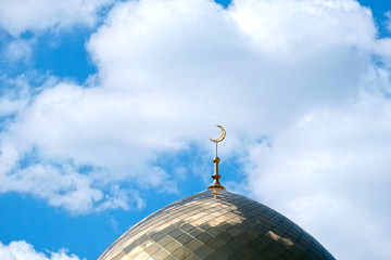 Fototapeta na wymiar The Golden minaret of the mosque. Muslim symbol on blue sky background with white . Crescent. Islam concept. Religious holiday.