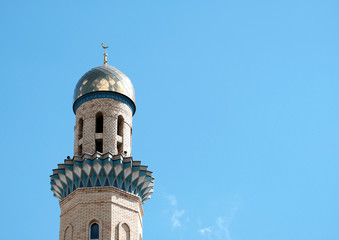 The Golden minaret of the mosque. Muslim symbol on blue sky background with white . Crescent. Islam concept. Religious holiday.