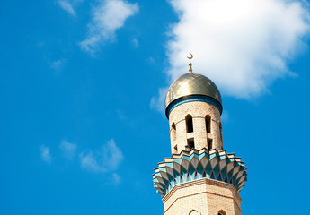 The Golden minaret of the mosque. Muslim symbol on blue sky background with white . Crescent. Islam concept. Religious holiday.
