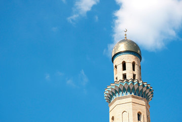 The Golden minaret of the mosque. Muslim symbol on blue sky background with white . Crescent. Islam concept. Religious holiday.