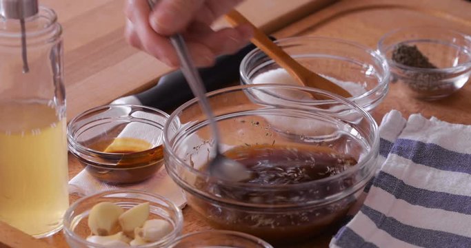 Steak making, preparing marinade, pouring apple vinegar into mixture, mixing using spoon, close-up